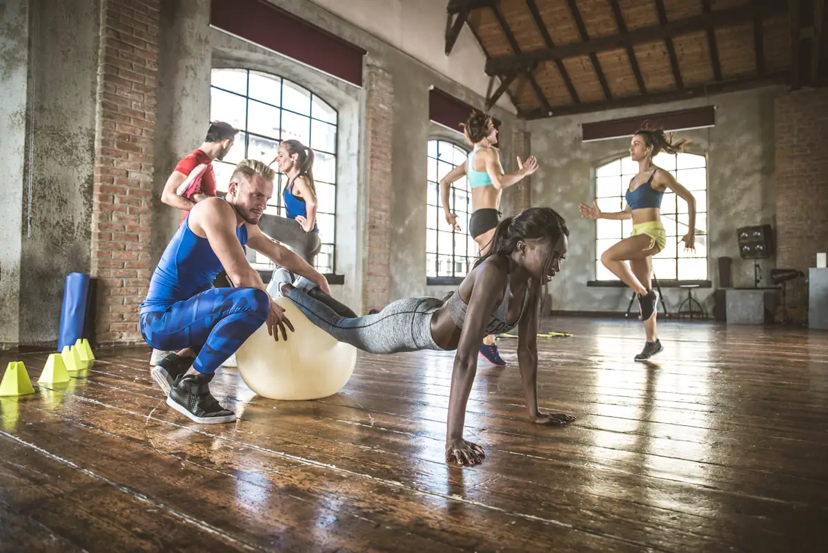 Un homme qui aide une femme à faire un gainage avec un ballon